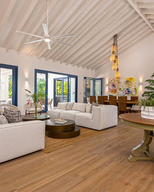 Sala principal de la villa de Sea Horse Ranch bajo el techo nuevo de vigas de madera, con los vanos hacia el jard&iacute;n