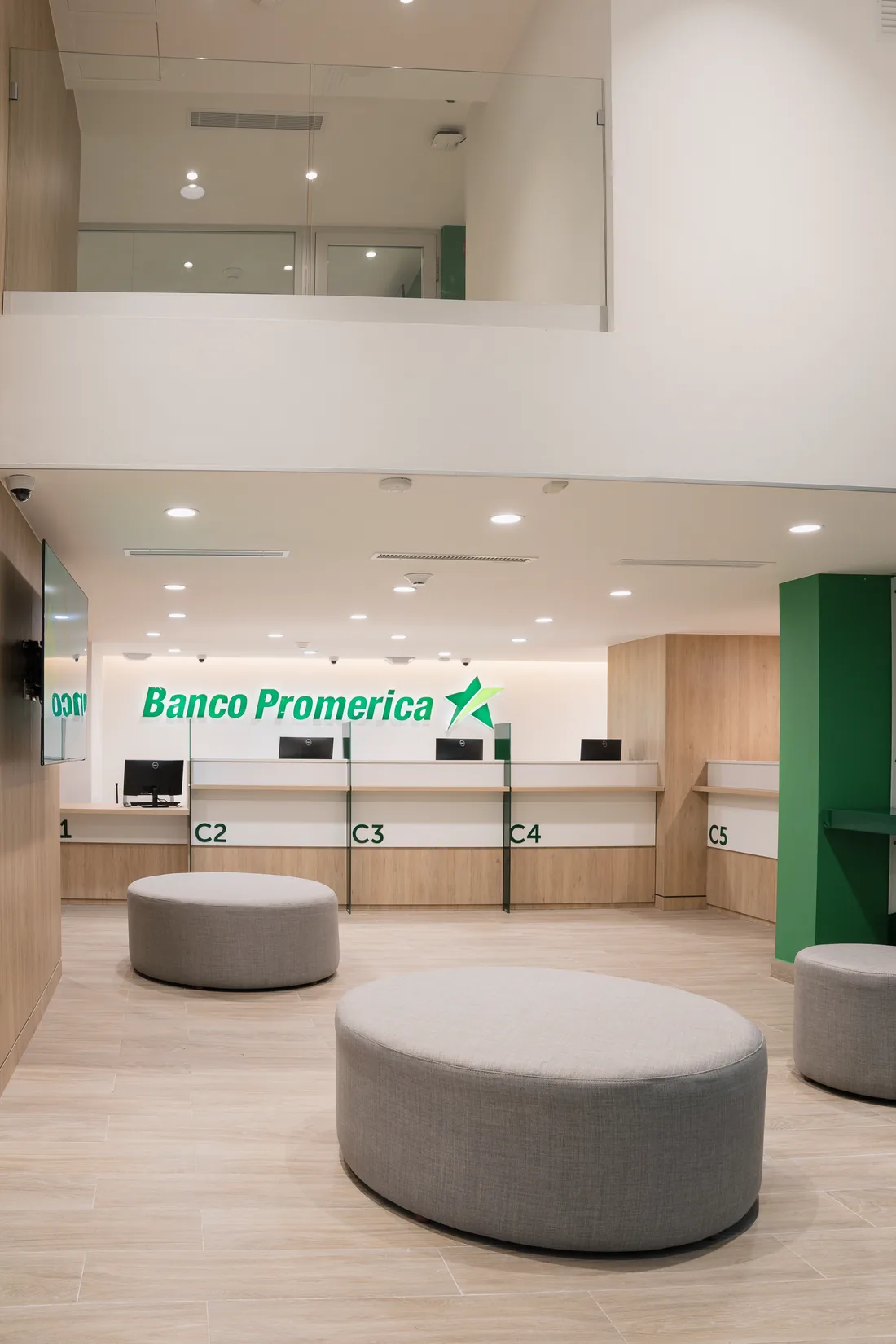 La doble altura sobre la línea de caja: el mezzanine con su antepecho y los puestos C2 a C5 bajo el rótulo del banco