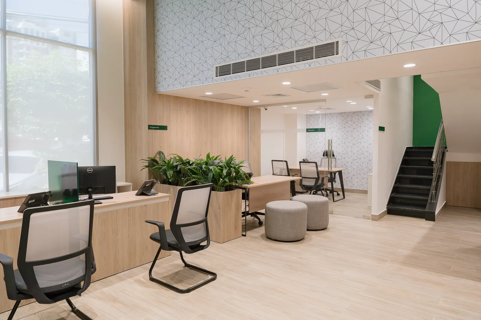 Vista general del área de trabajo con la escalera existente al fondo, los ventanales a la izquierda y el mural de líneas en el muro del mezzanine