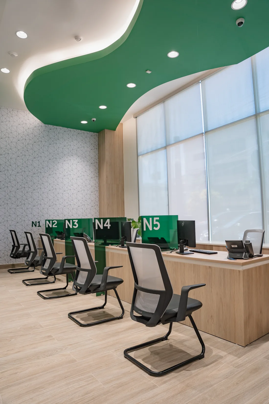 Cinco puestos de atención numerados de N1 a N5 frente al ventanal, bajo la curva del plafón verde
